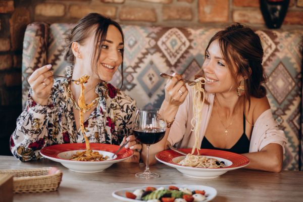 2 girls eating pasta in a restaurant